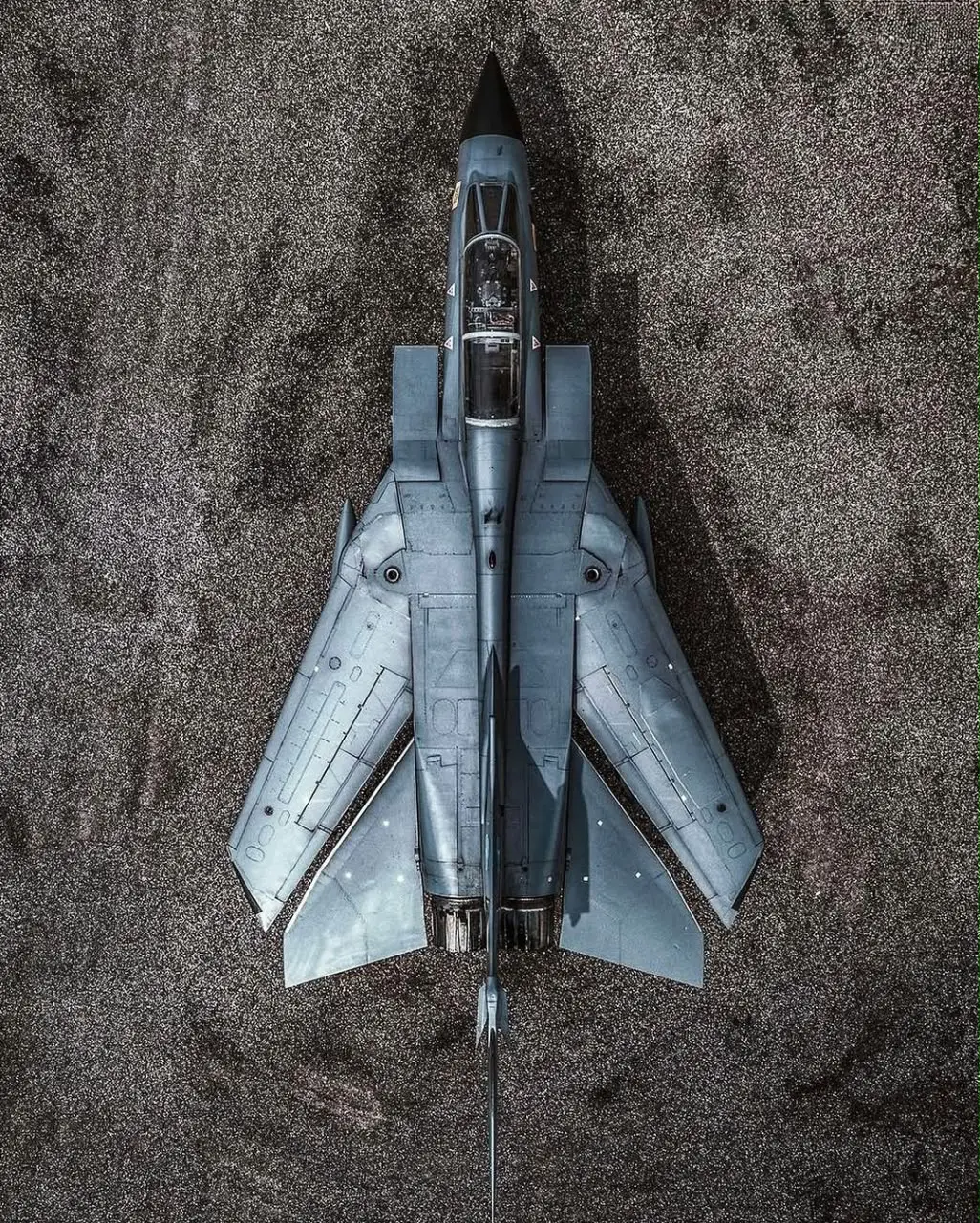 Top-down view of a swing-wing fighter jet on the ground